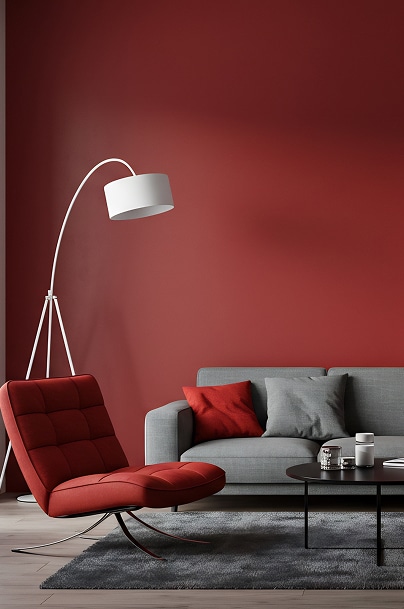 Mur rouge intense : idée déco pour salon moderne design. Intérieur moderne : mur rouge intense, canapé gris chiné, fauteuil lounge rouge tufté et lampe arc blanche.