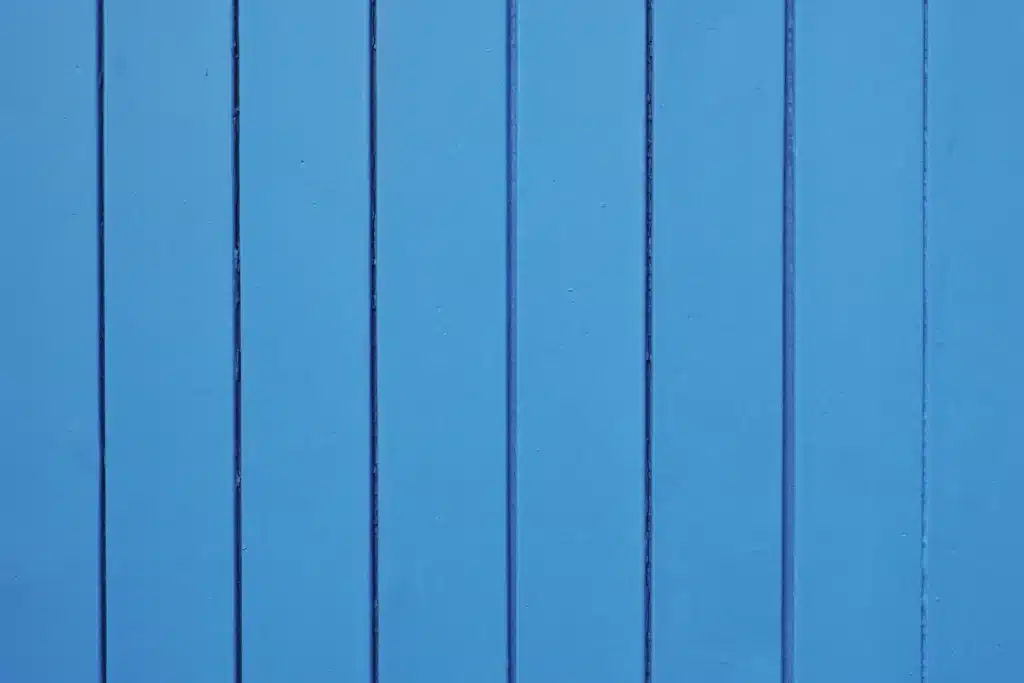 Surface de planches verticales peintes en bleu céruléen lumineux. Les rainures sombres contrastent avec le bois texturé.